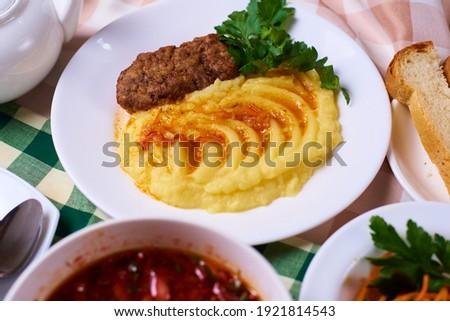 dinner set, mashed potatoes with a cutlet, a plate of soup, salad, tea and bread