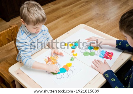 Two brothers coloring drawing of house with balloons with colored wax crayons. exercise for hand-eye coordination, stimulate imagination, creativity, develop fine motoric skills.