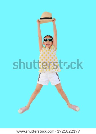 Cheerful asian little girl wearing sunglasses and straw hat jumping on cyan background isolated with clipping path. Summer and 