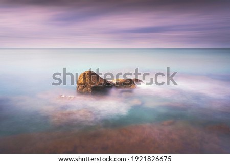 Rocks, soft sea and clouds in the sky, beautiful landscape in long exposure photography. Castiglioncello, Tuscany, Italy.
