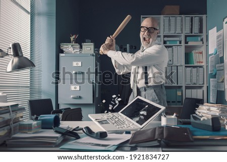 Crazy stressed businessman destroying his desk and laptop with a baseball bat, job burnout concept Royalty-Free Stock Photo #1921834727