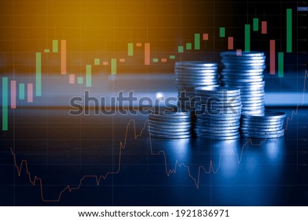 Stack of money coin and laptop computer with trading graph, financial investment concept with blue filter can be use as background Royalty-Free Stock Photo #1921836971
