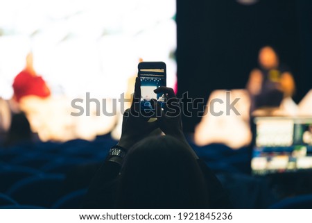 spectator photograph speakers on stage with their mobile phone. shooting video or photo with smartphone