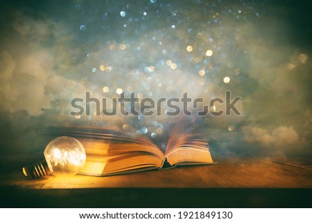 Magical image of open antique book over wooden table with glitter overlay Royalty-Free Stock Photo #1921849130