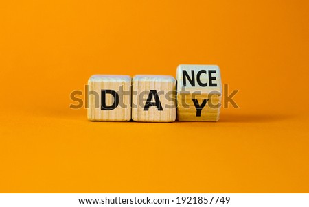 International Dance Day symbol. Turned the cube with words 'dance day'. Beautiful orange table, orange background, copy space. International Dance Day concept.