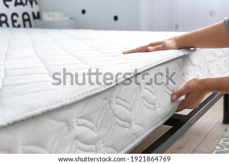 Woman putting soft orthopedic mattress on bed Royalty-Free Stock Photo #1921864769