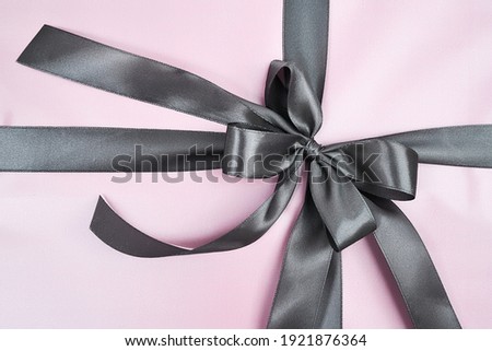 Holidays and celebration concept. Top view of a pink wrapped gift box with grey bow, close up shot. Present on Womens day for mother, wife, girlfriend or sister
