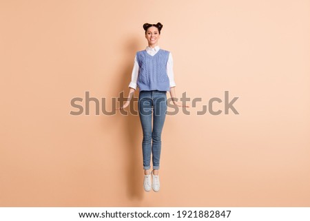 Full length photo of pretty charming young lady wear blue vest jumping high isolated beige color background