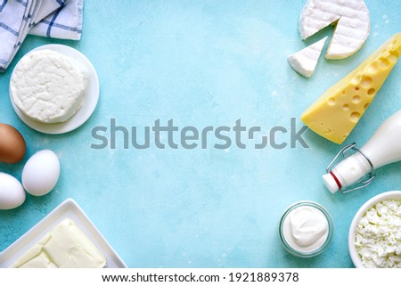 Fresh organic dairy products : butter, eggs, milk, cheese, cream on a light blue slate, stone or concrete background. Top view with copy space. Royalty-Free Stock Photo #1921889378