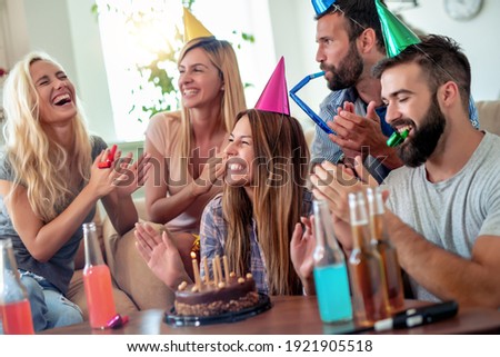 Celebration,friends, party and birthday concept - smiling women blows candles on her birthday cake.