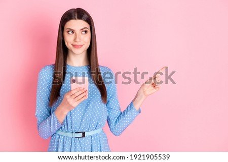Photo of young beautiful charming smiling dreamy girl point finger copysapce hold phone isolated on pink color background