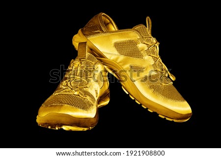 Golden sneakers black background isolated closeup, gold metal sport shoes, luxury running gumshoes, fashion yellow metallic fitness boots, athletic, football footwear, winner, victory, champion symbol