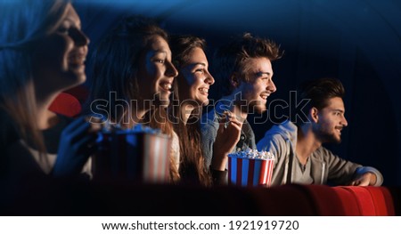 Group of teenager friends at the cinema watching a movie together and eating popcorn, entertainment and enjoyment concept Royalty-Free Stock Photo #1921919720