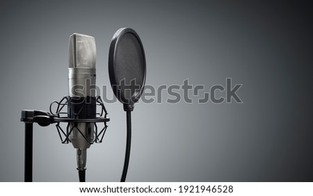 Studio microphone and pop shield on mic stand against gray background concept for podcast and presentation