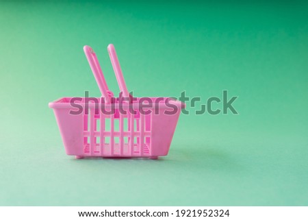 Little pink shopping basket isolated on green background. Shopping concept.