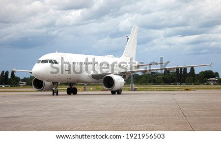 Passanger white plane lands. Airplane on the platform of Airport. Runway. Landing aircraft closeup. Mockup plane with place for text. Cloudy sky. Copy space. Cloudy sky. Royalty-Free Stock Photo #1921956503