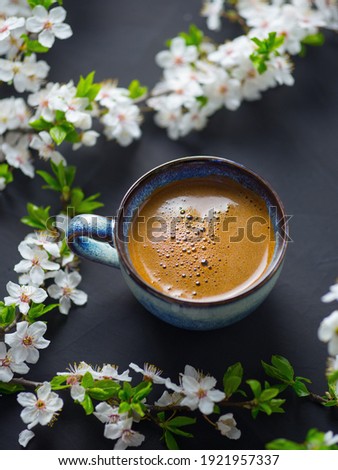 A Cup of fragrant freshly brewed coffee and blooming branches of spring cherries