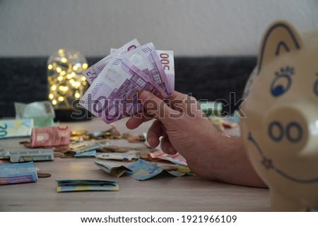 A selective focus shot of different euro banknotes with a white piggy bank on a wooden table
