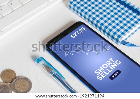 Short selling concept: smartphone on a white wooden table showing an app to trade stock option with the message "short selling now"