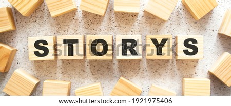 The word STORYS consists of wooden cubes with letters, top view on a light background. Work space.
