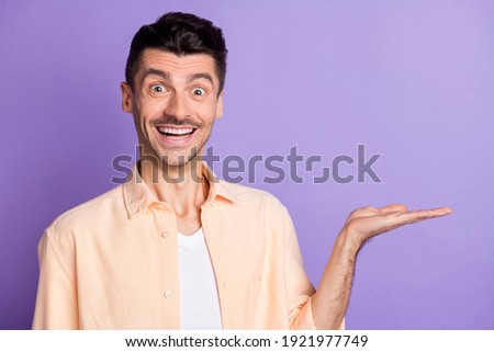 Photo of positive man hand demonstrate empty space wear beige shirt isolated violet color background