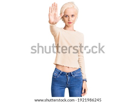 Young blonde woman wearing casual clothes doing stop sing with palm of the hand. warning expression with negative and serious gesture on the face. 