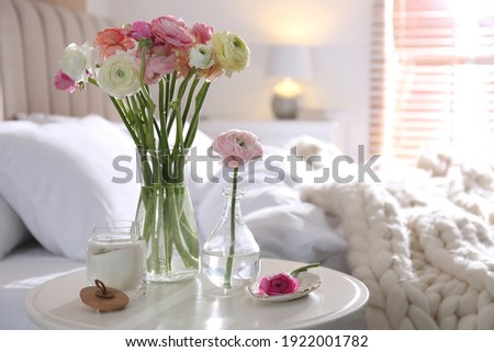Beautiful ranunculus flowers on table in bedroom, space for text