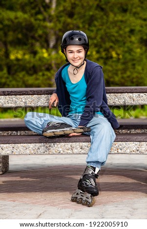 Teenage girl sitting and resting on bench after rollerblading
