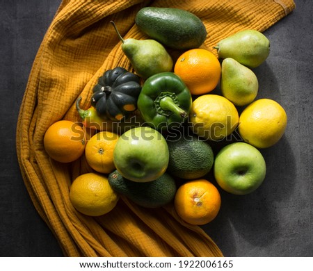 Yellow and green fruits and vegetables on a table. Top view photo of fresh lemons, grape, pepper, squash, apple, avocado and pear. Still life with seasonal fruits and vegetables. 