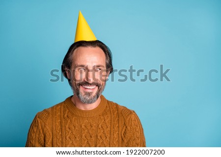 Photo portrait of happy smiling man wearing birthday hat curious looking blank space isolated on vivid blue color background
