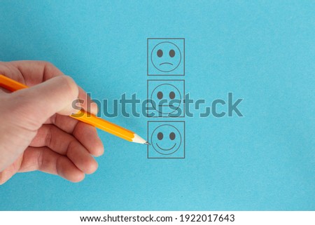In hand pencil draws emoticon icons on blue background.