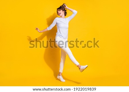 Photo of positive lady dance have fun wear white shirt trousers footwear isolated yellow color background