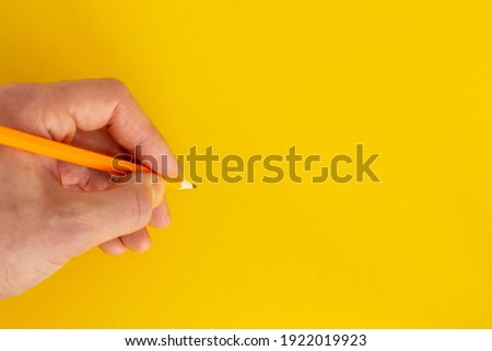 Hand holds a pencil on a colorful background.