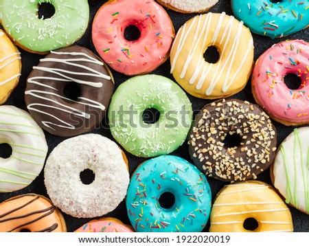 Donuts pattern. Top view of assorted glazed donuts. Colorful donuts with icing as background with copy space. Various colorful glazed doughnuts with sprinkles. Royalty-Free Stock Photo #1922020019