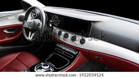 Red luxury modern car Interior. Steering wheel, shift lever and dashboard. Detail of modern car interior. Automatic gear stick. Part of leather seats with stitching in expensive car Royalty-Free Stock Photo #1922034524