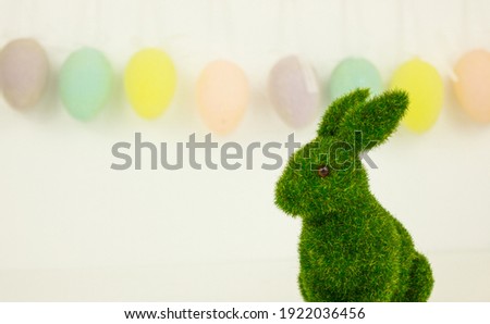Green Easter bunny on a background of garlands of decorative eggs. Festive background. Happy Easter. Place for text.