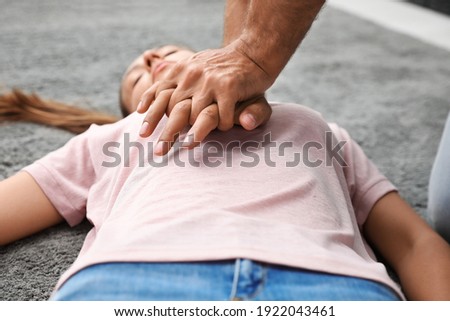 Man performing CPR on unconscious young woman indoors, closeup. First aid Royalty-Free Stock Photo #1922043461