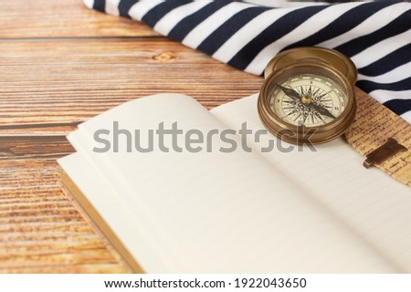 The compass, sea ​​blouse and open notebook in vintage style are on a wooden background. Free space for text.