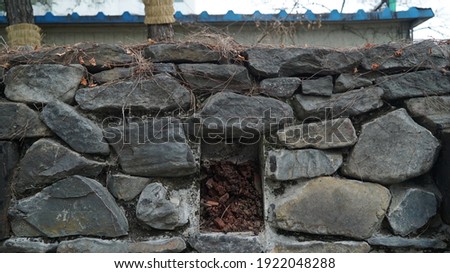 Wooden Decorated Large Rocky Stone Wall on the Street