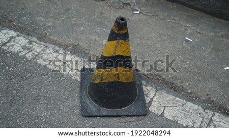 Black and Yellow Striped Traffic Cone on the Asphalt Road