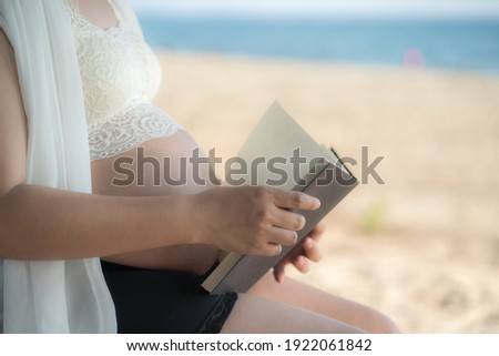 Asian Pregnant woman reading a book with copy space. (Vintage tone) at beach .Young pregnant woman .
