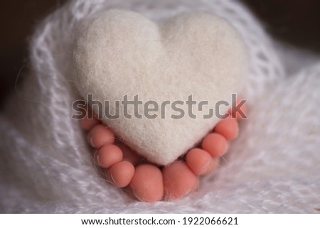 legs and toes of a newborn in a soft white blanket with a heart