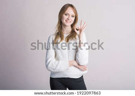 Portrait of a stylish girl on a white background in the studio who shows Okay Agree