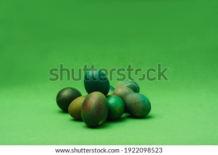 Bunch of green painted Easter eggs on green background. Monochro