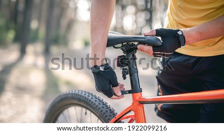 Rider adjusting seat height on bicycle standing in sunny forest Royalty-Free Stock Photo #1922099216