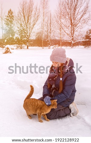 A girl strokes a red cat. Love for animals. Artistically colored and tinted photography