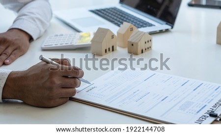 Young man hand holding a pen, contract, insurance concept, home insurance agent, small sample on the table Demonstrating home protection for customers interested in insurance