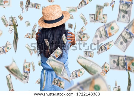 Young indian girl wearing summer hat hugging oneself happy and positive from backwards. self love and self care