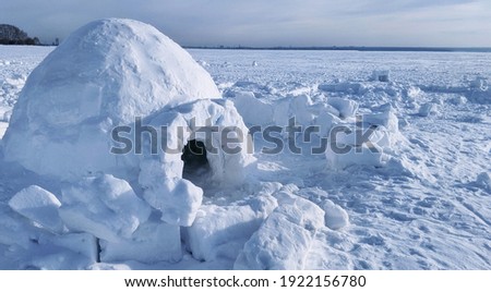 igloo and snow shelter in high snowdrift with mountains peaks on background