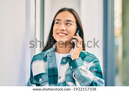 Young latin girl smiling happy talking on the smartphone at the city.